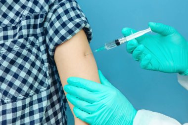 Doktorun elleri çok yakın. Doktor kişiye bir enjeksiyon yapar. Mevsimlik aşı. İnokülasyon. Coronavirus aşısı. COVID 19. küresel salgın.
