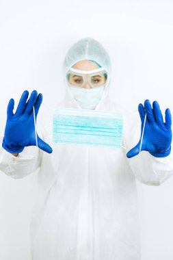 Elinde dezenfektanla beyaz arka planda duran tıbbi maskeli bir doktor. Coronavirüs salgınında dezenfektan kullanımı. COVID 2019. Doktorlara yardım et - evde kal.