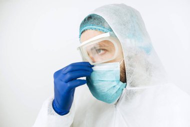 Hastanede vardiyadan sonra yorgun doktorların yakın plan portresi. Koruyucu giysili doktor. Gözlük, maske, beyaz arka planda eldivenler. Doktor koronavirüslü hastaları tedavi ediyor. Covid 2019