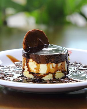 Beyaz tabakta servis edilen kremalı tatlı ve çikolata sosu.