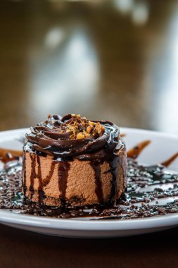 Çikolata soslu küçük çikolatalı pasta, beyaz tabakta servis edilir.