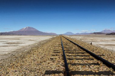 Bolivya 'da çölün ortasında, arkasında dağlar olan bir demiryolu manzarası