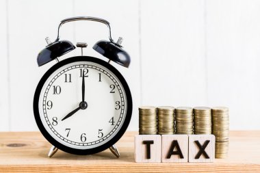 Tahta blokta siyah alarm saati ve vergi mektubu yığını, Vergi Tasarruf Zamanı