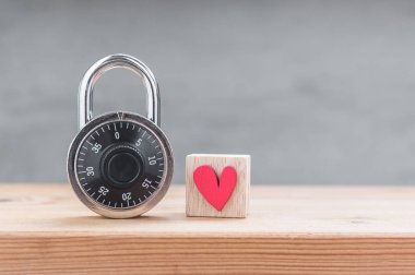 Ahşap küpte kırmızı kalp, ahşap masada asma kilit kombinasyonu.