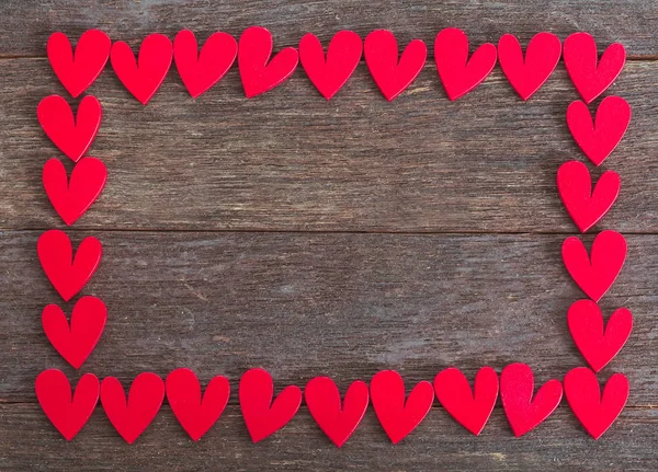 Ahşap arka planda kalpler tarafından yapılmış bir çerçeve