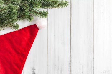 Metin kopyalama yeri olan beyaz rustik ahşap arka plan üzerinde santa claus şapka ile Noel köknar ağacı dalları