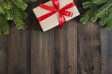 Noel köknar ağacı dalları ve metin için kopya yer karanlık rustik ahşap zemin üzerine hediye kutusu