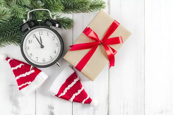 Noel ağacı dalları Noel Baba şapkası, hediye kutusu ve beyaz rustik ahşap zemin üzerinde alarm saati metin alanı için fotokopi alanı