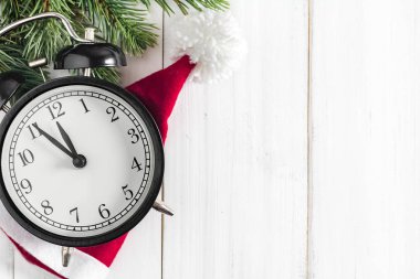 Noel ağacı dalları alarmlı ve Noel Baba şapkası beyaz rustik ahşap arka planda metin alanı için kopyalanmış