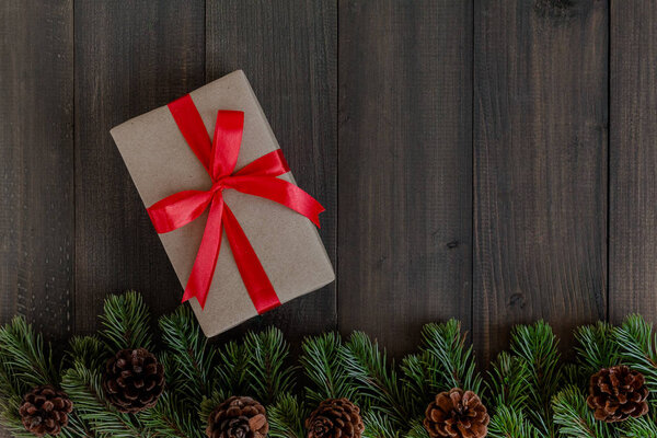 Christmas fir tree branches and gift box on dark rustic wooden b