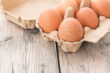 Tahta masadaki kutuda taze kahverengi yumurtalar.
