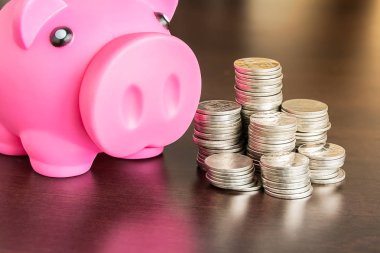 Ahşap masada kumbarası olan bir yığın bozuk para.