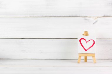 Beyaz ahşap arka planda sanat tahtasıyla kırmızı kalp boyası. Aşk 