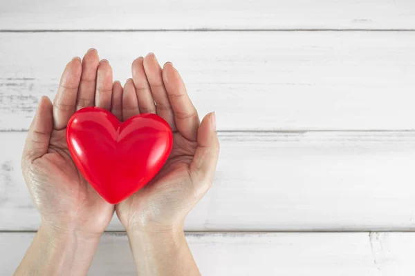 Hands of Woman hold red heart shaped over wood white background. — 스톡 사진