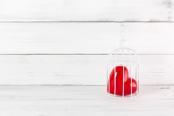 Red Heart inside Bird Cage on white wood background. Freedom Lov