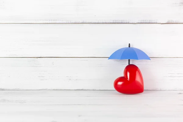 Czerwone serce pod parasolem na białym tle drewna. Proect miłość o — Zdjęcie stockowe