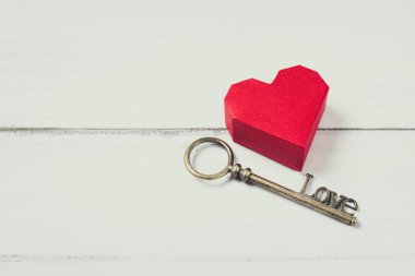 Beyaz ahşap arka planda antika anahtarı olan kırmızı kağıt kalp. Başarı
