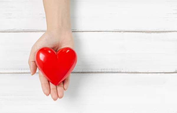 Woman Hand Hold Red Heart em fundo de madeira branca. Proteger o amor — Fotografia de Stock