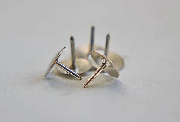 office buttons in the form of carnations with a wide hat made of white shiny metal, close-up on a white background, close up of safety pin