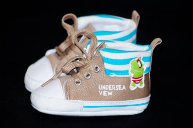 Siyah arka planda bir çift bebek ayakkabısı..