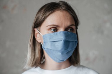 Maskeli, kısa saçlı, beyaz tişörtlü genç bir kız, evde, yakın plan. Coronavirus. Karantina