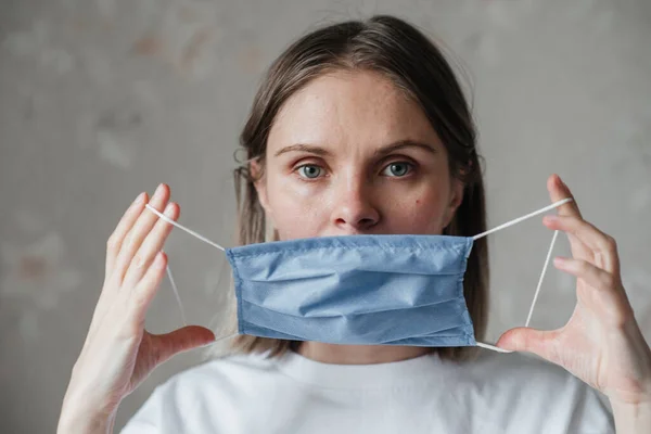 Maskeli, kısa saçlı, beyaz tişörtlü genç bir kız, evde, yakın plan. Coronavirus. Karantina