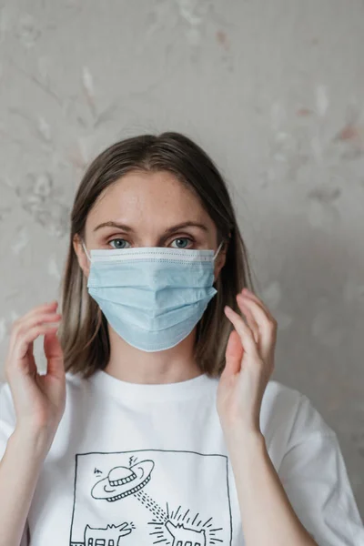 Maskeli, kısa saçlı, beyaz tişörtlü genç bir kız, evde, yakın plan. Coronavirus. Karantina