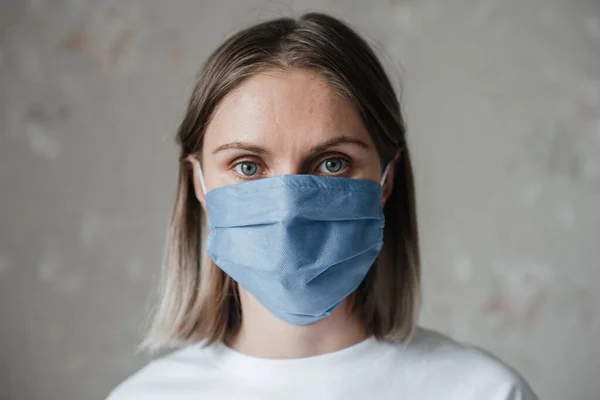 Maskeli, kısa saçlı, beyaz tişörtlü genç bir kız, evde, yakın plan. Coronavirus. Karantina