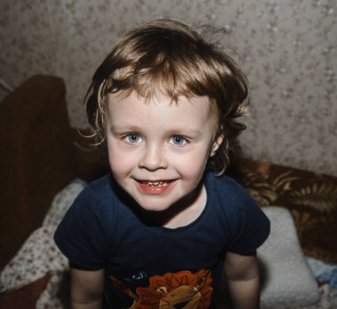 Üç yıllık mutlu çocuk yatakta oynar ve güler. Yakın plan.