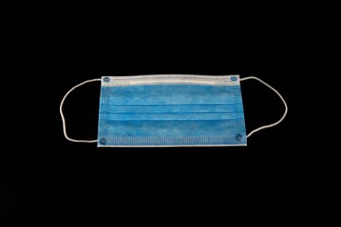 Bir COVID-19 koruma maskesi siyaha izole edilmiş. 3 katlı cerrahi yüz maskesi.