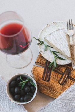 Siyah zeytinli peynir ve beyaz masada kırmızı şarap.