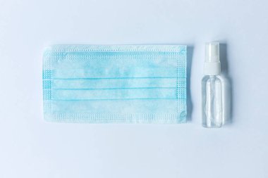 El dezenfektanı ve kullan-at hijyenik ya da beyaz arka planda tıbbi maske. Coronavirus COVID-19. Üst görünüm