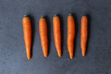 Gri beton bir masada taze havuçlarla bezenmiş düz bir bileşim. Taze turuncu havuç. Üst görünüm.