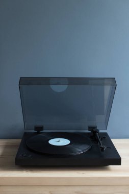 Masada vinil plaklı siyah bir pikap var. Boş yer