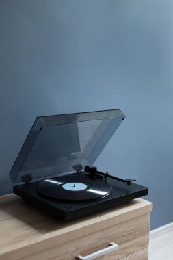 Vinil disk çalan bir pikap. Renk duvarının yanındaki masada vinil diski olan bir plak çalar. Boş yer