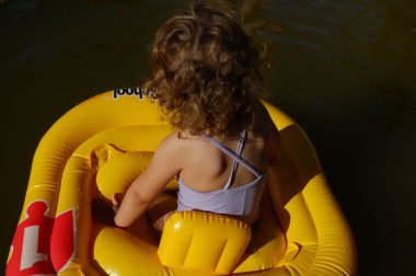 Çocuk bir sandal üzerinde gölde yüzüyor.