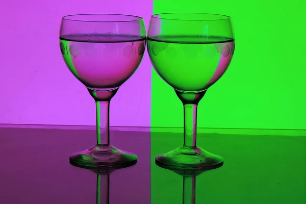 Pohár vízzel a egy rózsaszín és zöld háttér — Stock Fotó