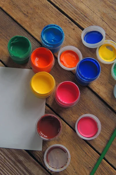Jogo de nove pinturas de guache de cores em jarros na mesa de madeira. Foco em vermelho — Fotografia de Stock
