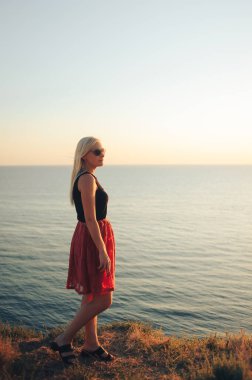 Denizde gün batımına bakan bir kızın görüntüsü.