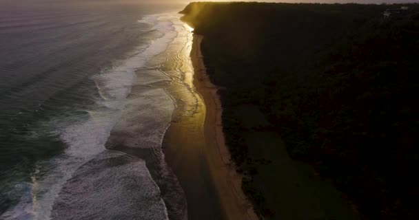 Images aériennes de drones montrant des vagues océaniques se brisant avant le rivage au coucher du soleil. Bali, Indonésie — Video