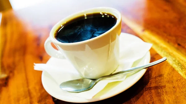 Czarna kawa w białe filiżanka na brązowy drewniany stół — Zdjęcie stockowe