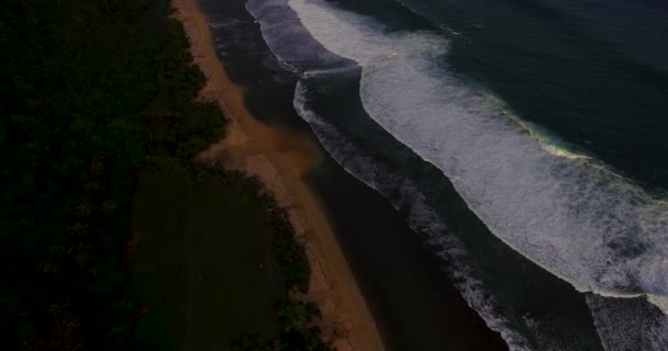 Запись с воздушного беспилотника, где океанские волны ломаются перед берегом на закате. Бали, Индонезия — стоковое видео