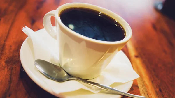 茶色の木製のテーブルの上に白いカップでブラック コーヒー — ストック写真
