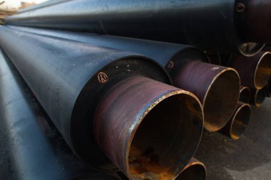 büyük siyah çelik boru ile ısı yalıtımı inşaat sitesinde yakın çekim bir plastik tüp sarıcı