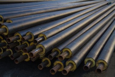 kaldırımda bir grup yalan bir plastik tüp sarıcı inşaat sitede ısı yalıtımı ile siyah çelik boru