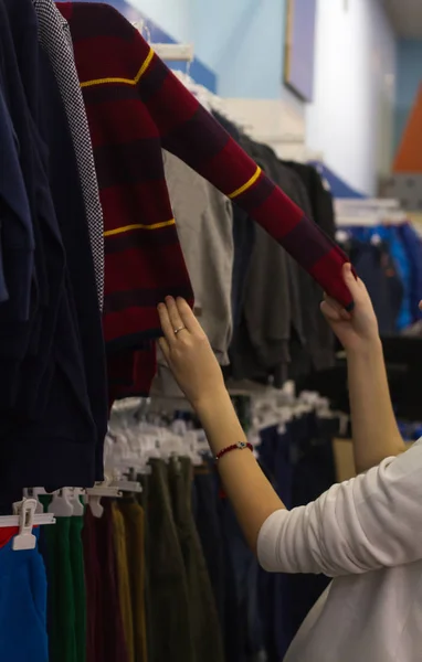 Mujer de compras, mano que mira el suéter del soporte, niño en la tienda —  Fotos de Stock