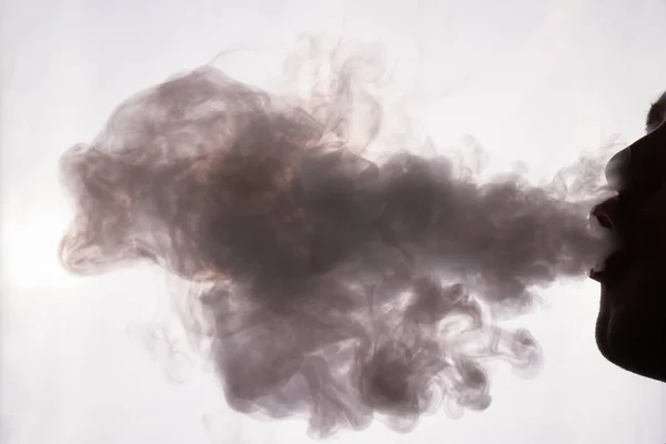 A young man smokes hookah part of the face in the shadow release