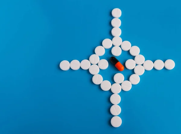 Concettuale per la produzione farmaceutica. Pillola bianca farmaci rotondi disposti su uno sfondo blu sotto forma di vista nel centro pillola colorata Fotografia Stock