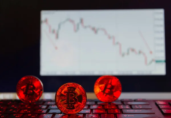 Bitcoin sulla tastiera in rosso, sullo sfondo del grafico discendente Foto Stock