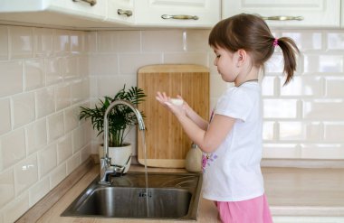 Kız mutfakta ellerini sabunla yıkıyor..